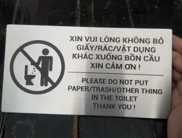 Bảng nội quy toilet cấm bỏ giấy rác cầm trên tay
