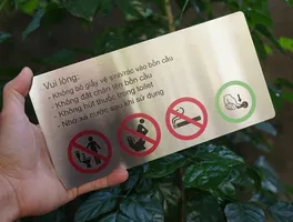 Bảng nội quy toilet 4 nội dung cầm trên tay nền lá cây