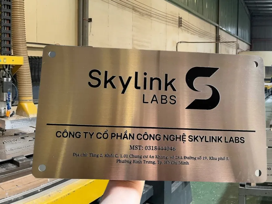 Làm Bảng Inox Ăn Mòn Vàng Hồng Hairline – Ăn Mòn Logo Thương Hiệu Làm bảng hiệu inox ăn mòn phôi vàng hồng rose gold hairline, ăn mòn logo thương hiệu phức tạp sắc nét dưới 1mm, góc bo tròn, lỗ vít ẩn tinh tế