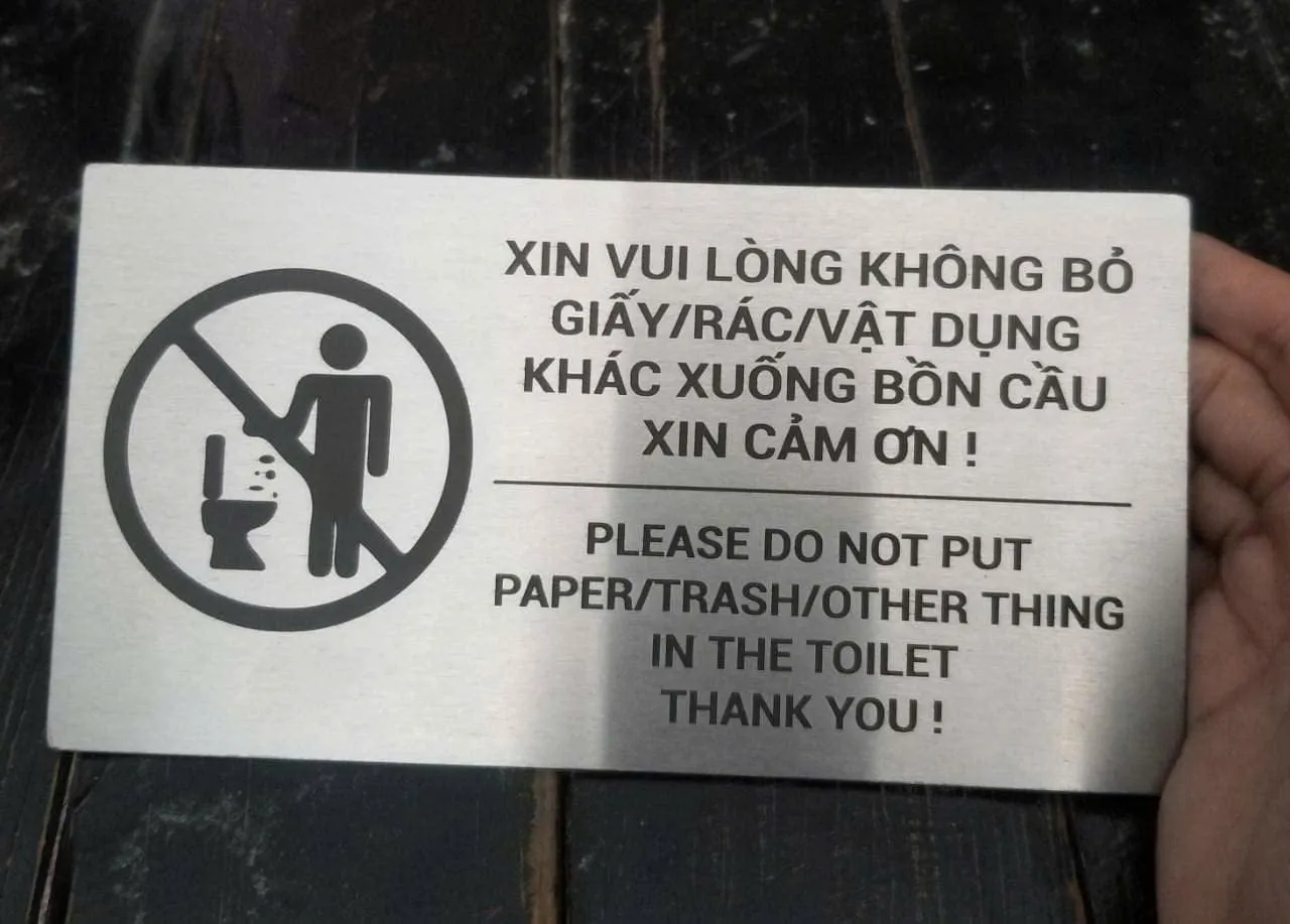 Bảng nội quy toilet cấm bỏ giấy rác cầm trên tay
