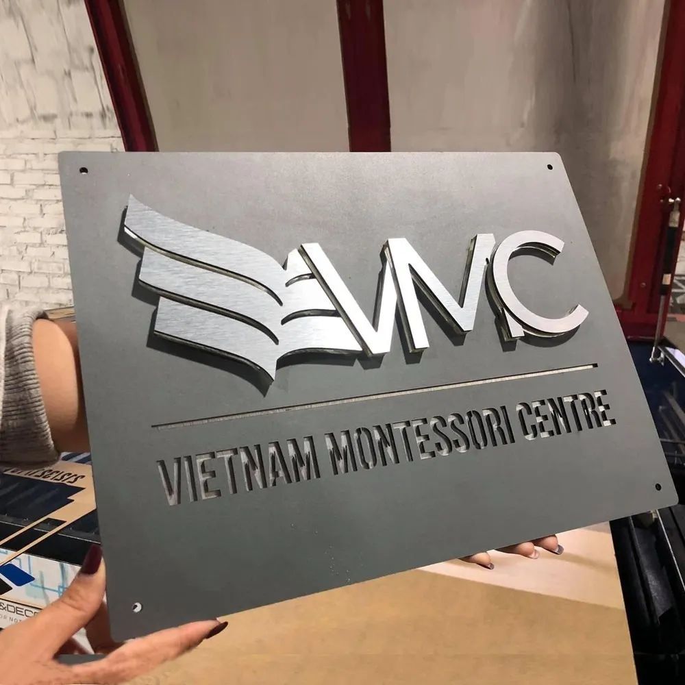 Bảng hiệu công ty inox 3D cho trung tâm giáo dục Vietnam Montessori Centre Bảng hiệu công ty inox xám khói logo nổi 3D bạc xước cho trung tâm giáo dục – Bảng Hiệu Vàng