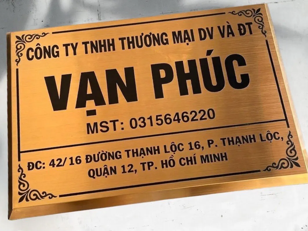 Cận cảnh chữ khắc ăn mòn kim loại sơn tĩnh điện đen trên bảng hiệu inox vàng xước Chữ khắc ăn mòn inox sơn tĩnh điện đen trên bảng hiệu công ty vàng xước