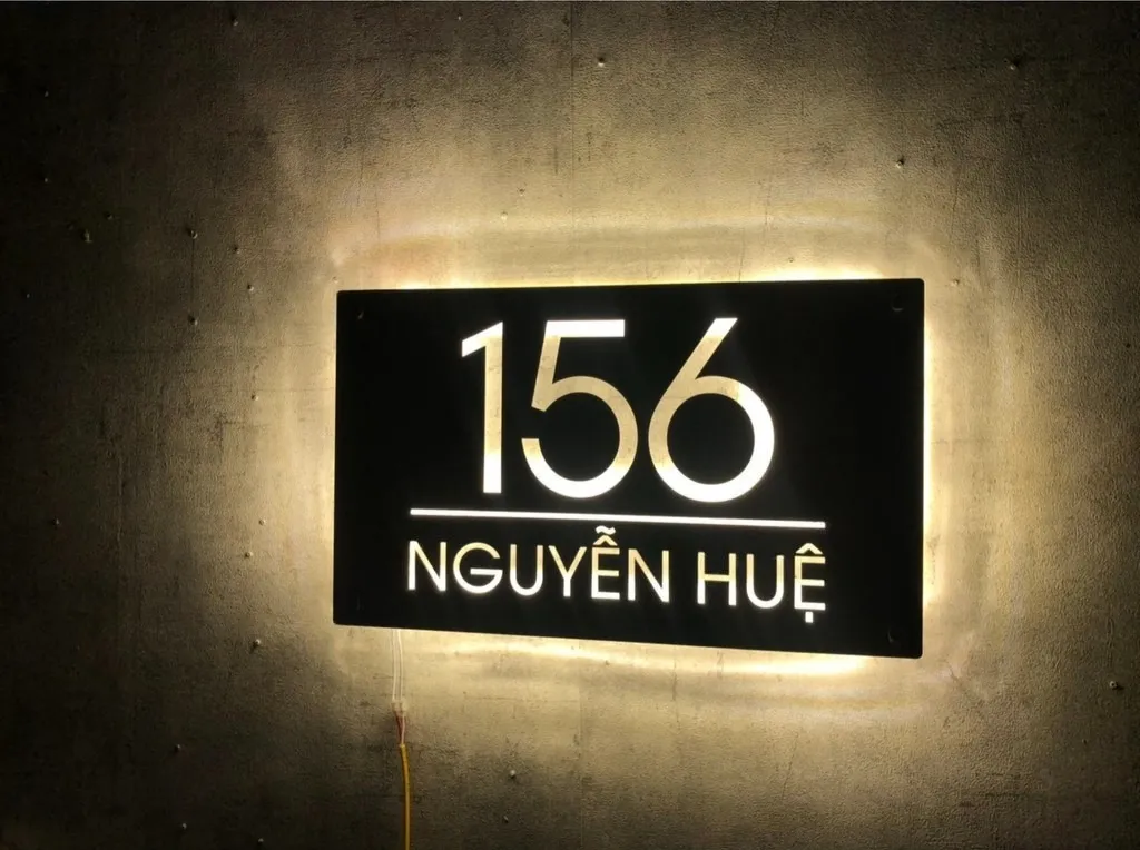 Bảng số nhà inox LED halo glow sáng ban đêm trên tường bê tông Bảng số nhà inox 304 hairline đèn LED halo backlit phát sáng ban đêm, hiệu ứng hào quang vàng ấm trên tường