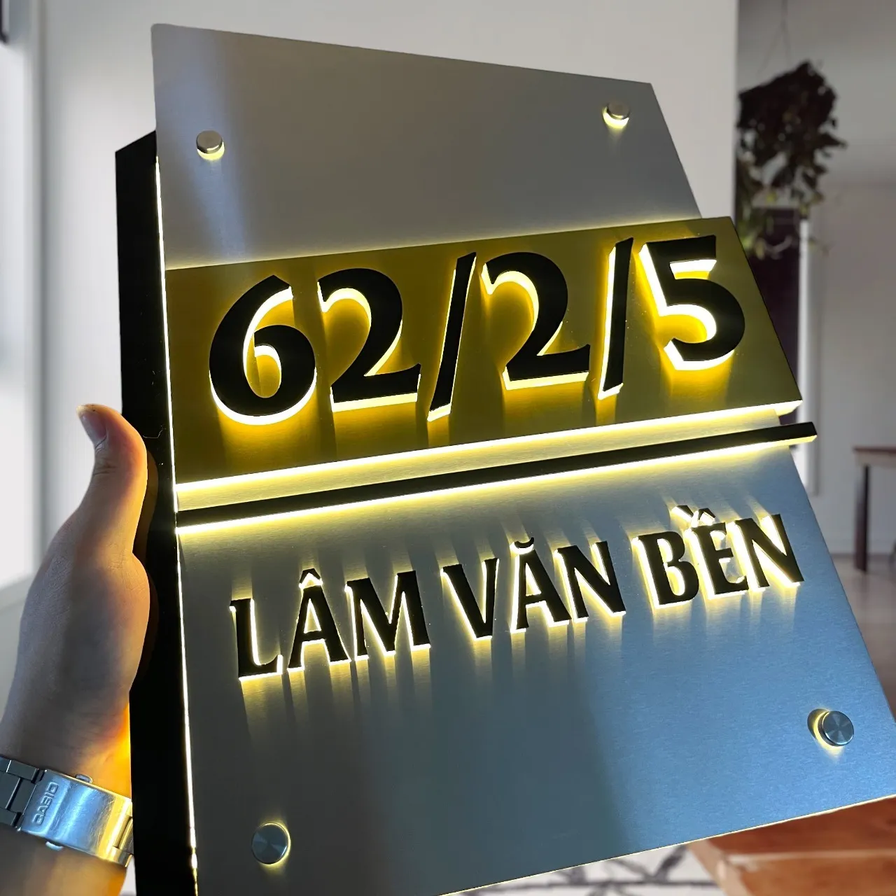 Bảng số nhà LED vàng – cận cảnh góc nghiêng thấy hào quang vàng sáng chân chữ đen nổi 3D Bảng số nhà inox bạc vàng LED vàng – hào quang ánh vàng sáng chân chữ nổi 3D nhìn từ góc nghiêng gần