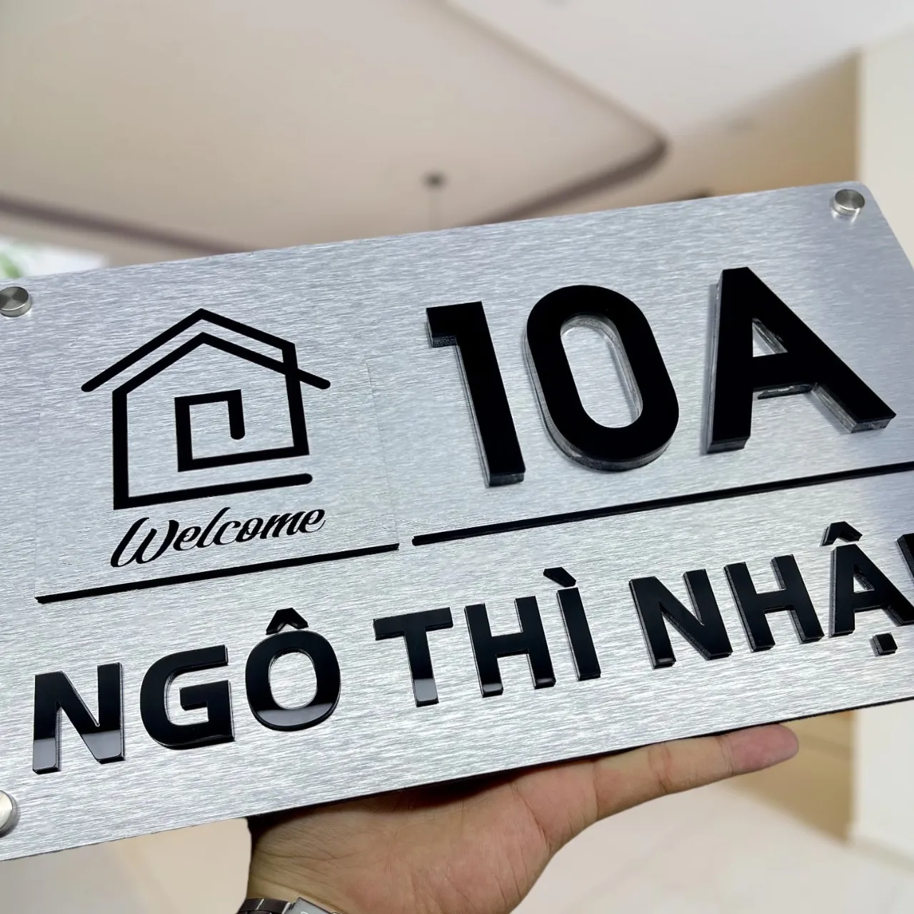 Cận cảnh icon Welcome và chữ nổi 3D đen bóng trên bảng số nhà inox Cận cảnh icon ngôi nhà cách điệu và chữ Welcome thư pháp trên bảng số nhà inox bạc xước