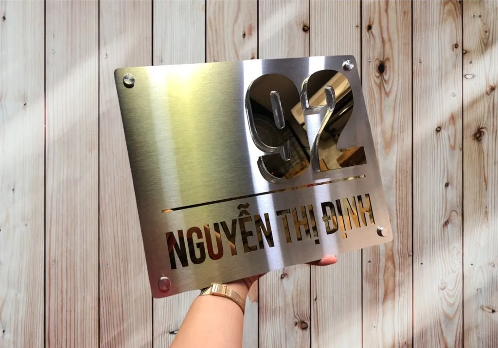 Bảng số nhà inox tối giản siêu mỏng 5mm chụp trên nền gỗ tự nhiên – vẻ đẹp chất liệu thuần túy Bảng số nhà inox xước bạc vàng gương tối giản siêu mỏng 5mm đặt trên nền gỗ tự nhiên – tương phản chất liệu sang trọng