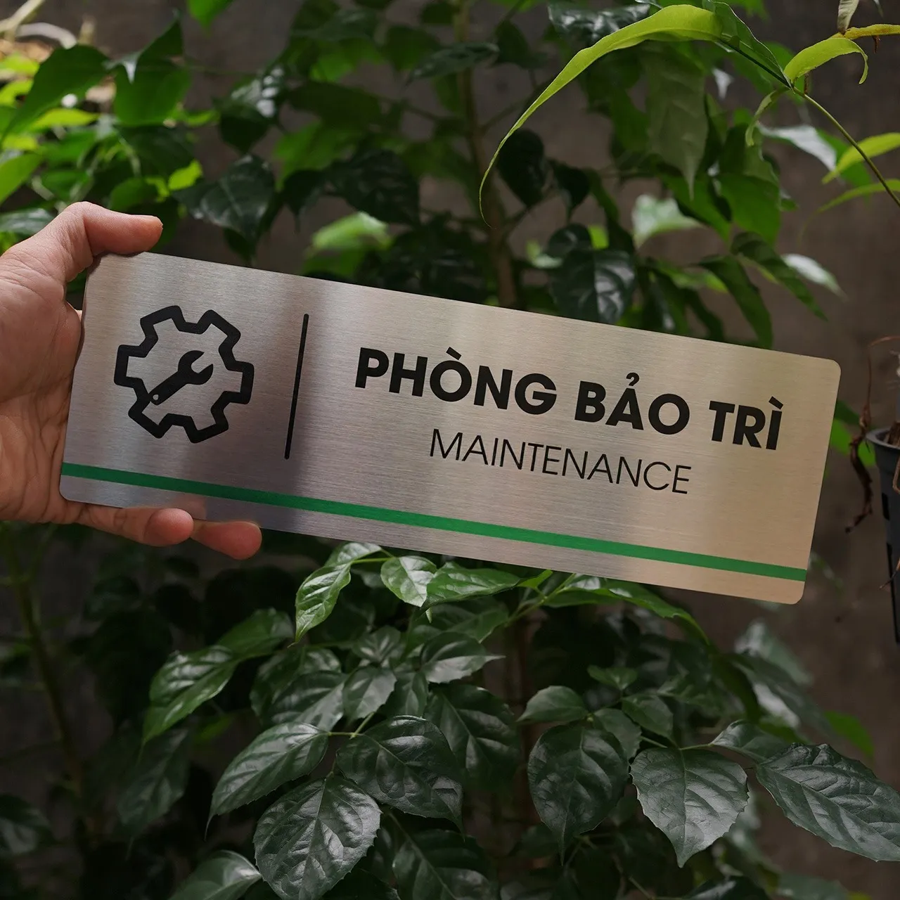 Phối cảnh thực tế bảng tên phòng inox 304 – Bảng Hiệu Vàng Bảng tên phòng inox 304 cầm trên tay, phối cảnh thực tế ngoài trời