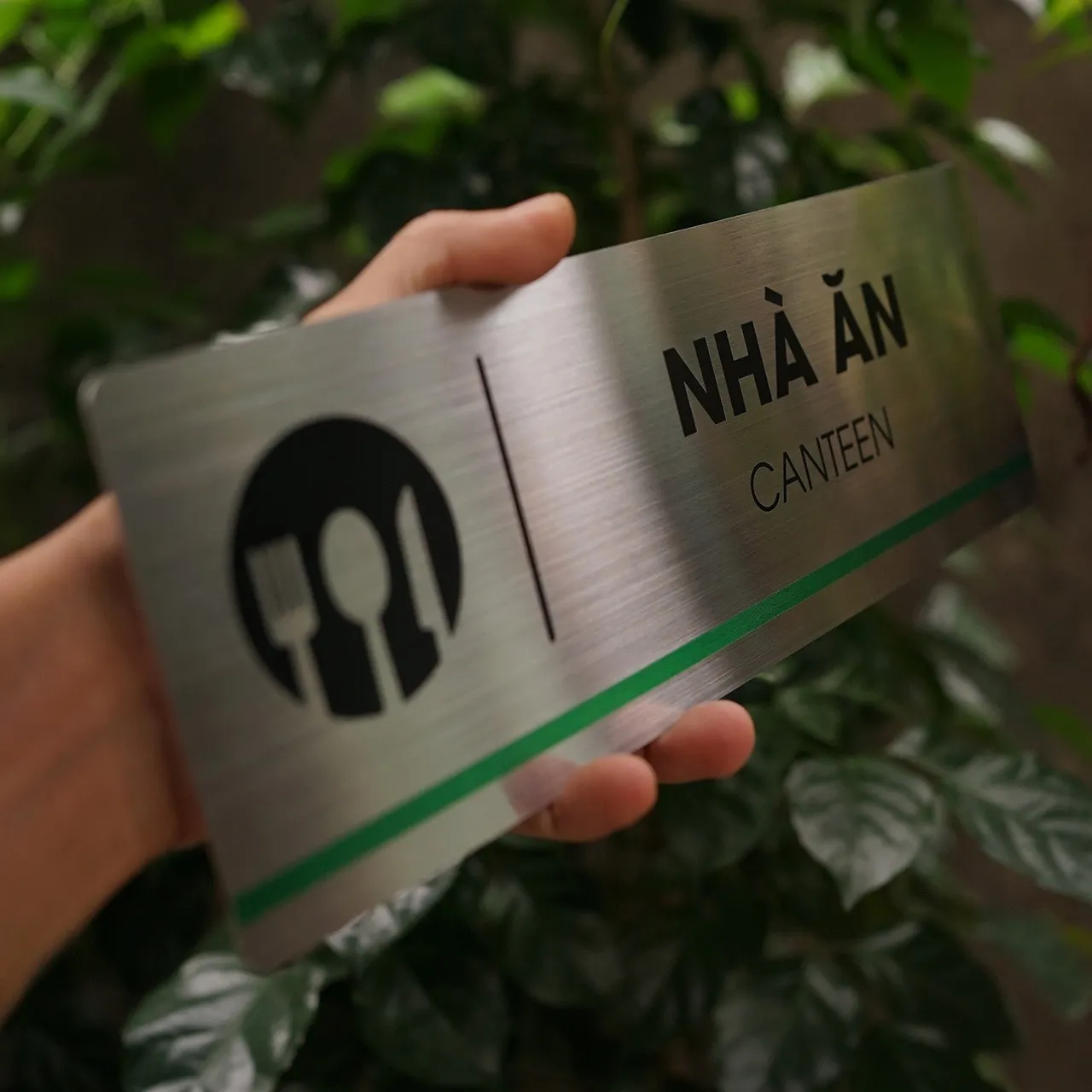 Cận cảnh icon đĩa nĩa thìa dao ăn mòn hóa học trên bảng tên nhà ăn canteen inox 304