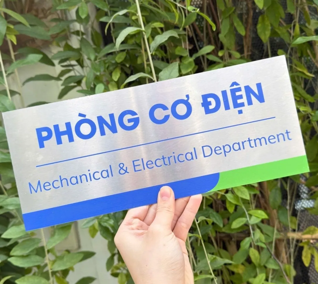 Bảng tên phòng cơ điện inox phay xước cầm tay nhìn góc nghiêng ngoài trời
