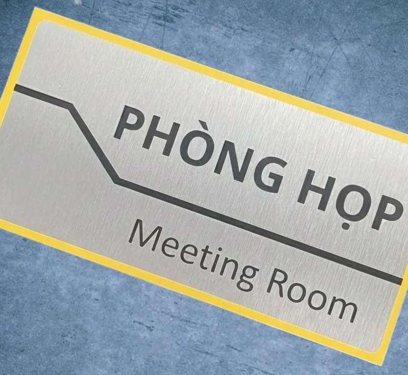 Bảng tên phòng họp viền vàng góc nghiêng cận cảnh trên nền đá xanh