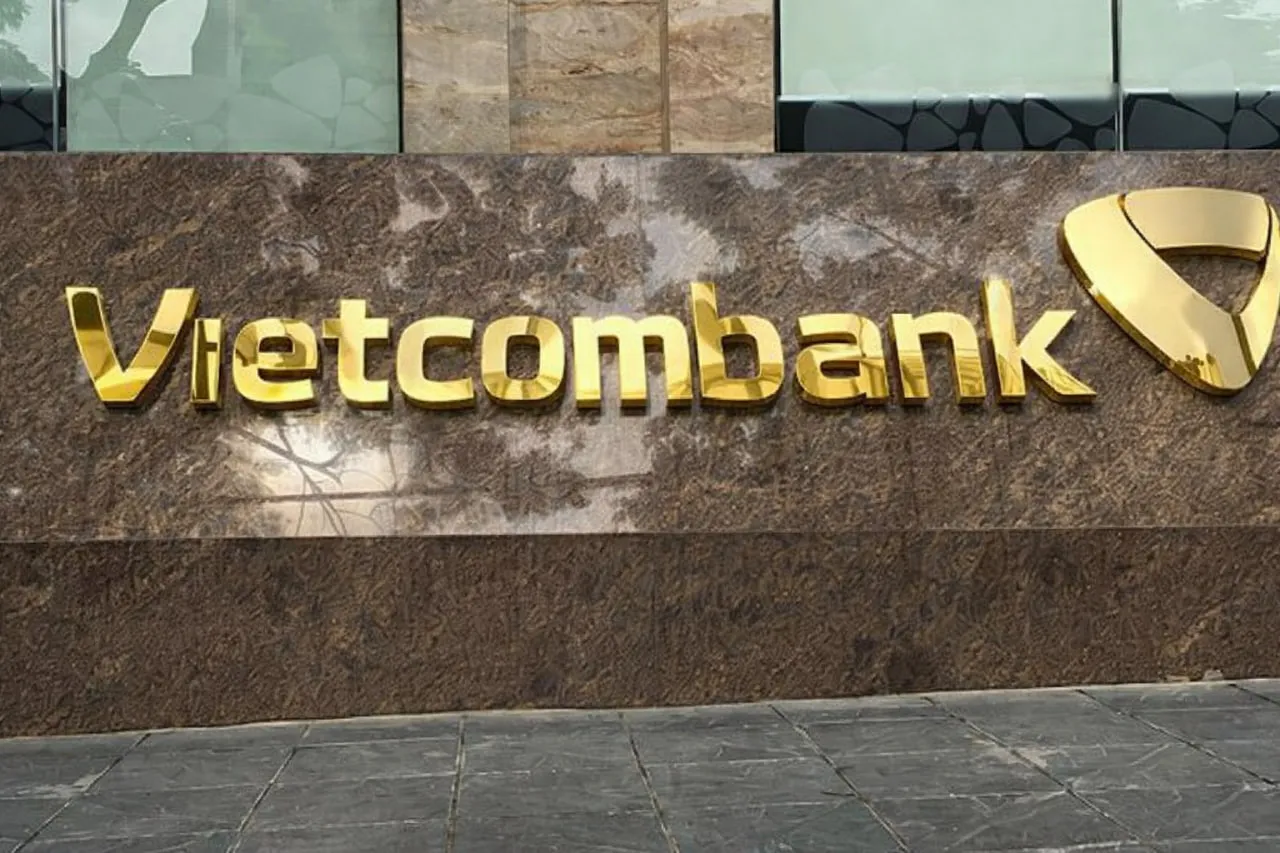 Biển quảng cáo Vietcombank chữ nổi inox vàng gương phản chiếu trên tường đá hoa cương