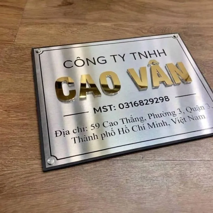 Góc nghiêng bảng hiệu inox chữ nổi 3D vàng gương – thấy bóng đổ chiều sâu bảng hiệu inox chữ nổi 3D vàng gương nền bạc xước bóng đổ góc nghiêng