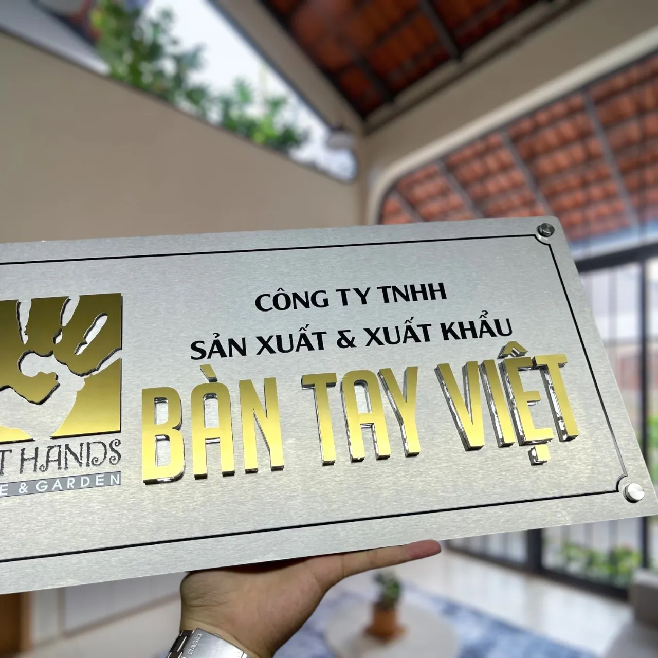 Bảng hiệu công ty inox vàng gương nhìn góc nghiêng phải, thấy rõ chữ nổi 3D và vít góc inox trang trí