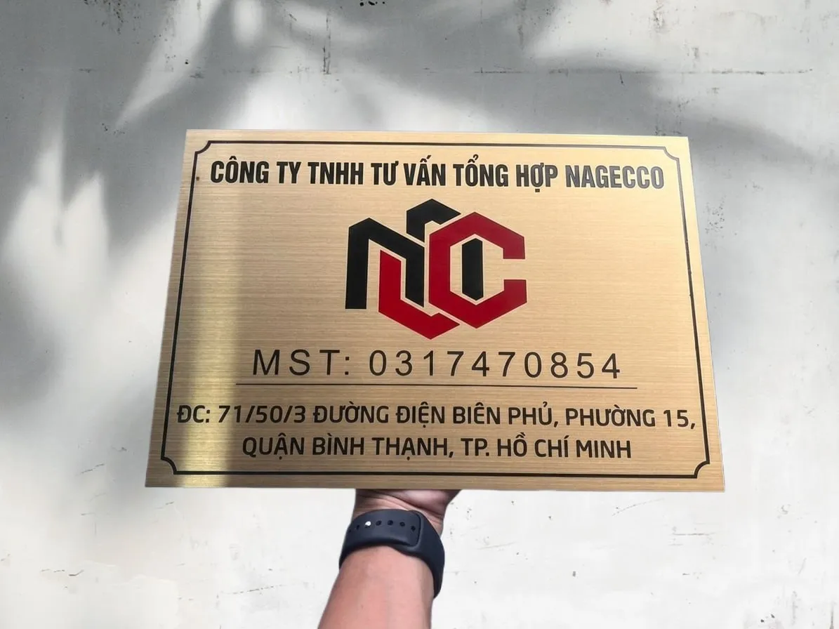 Phối cảnh thực tế bảng hiệu công ty inox 304 vàng xước chữ ăn mòn sơn tĩnh điện đỏ đen khung viền — hoàn thiện sẵn sàng lắp đặt