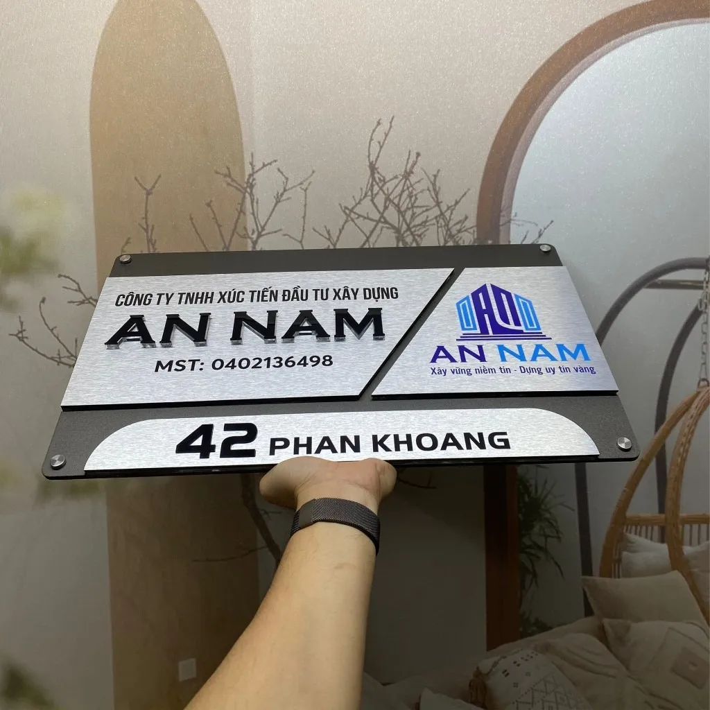 Bảng hiệu công ty inox 3 mảnh chữ nổi 3D logo màu nhìn mặt trước chính diện trong nhà Bảng hiệu công ty inox xám khói bạc 3 mảnh chữ nổi 3D đen logo màu xanh nhìn mặt trước chính diện