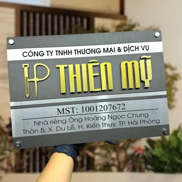 Bảng hiệu công ty inox xám khói chữ nổi 3D nhìn mặt trước chính diện ngoài trời Bảng hiệu công ty inox xám khói bạc xước 2 lớp chữ nổi vàng có logo chụp ngoài trời