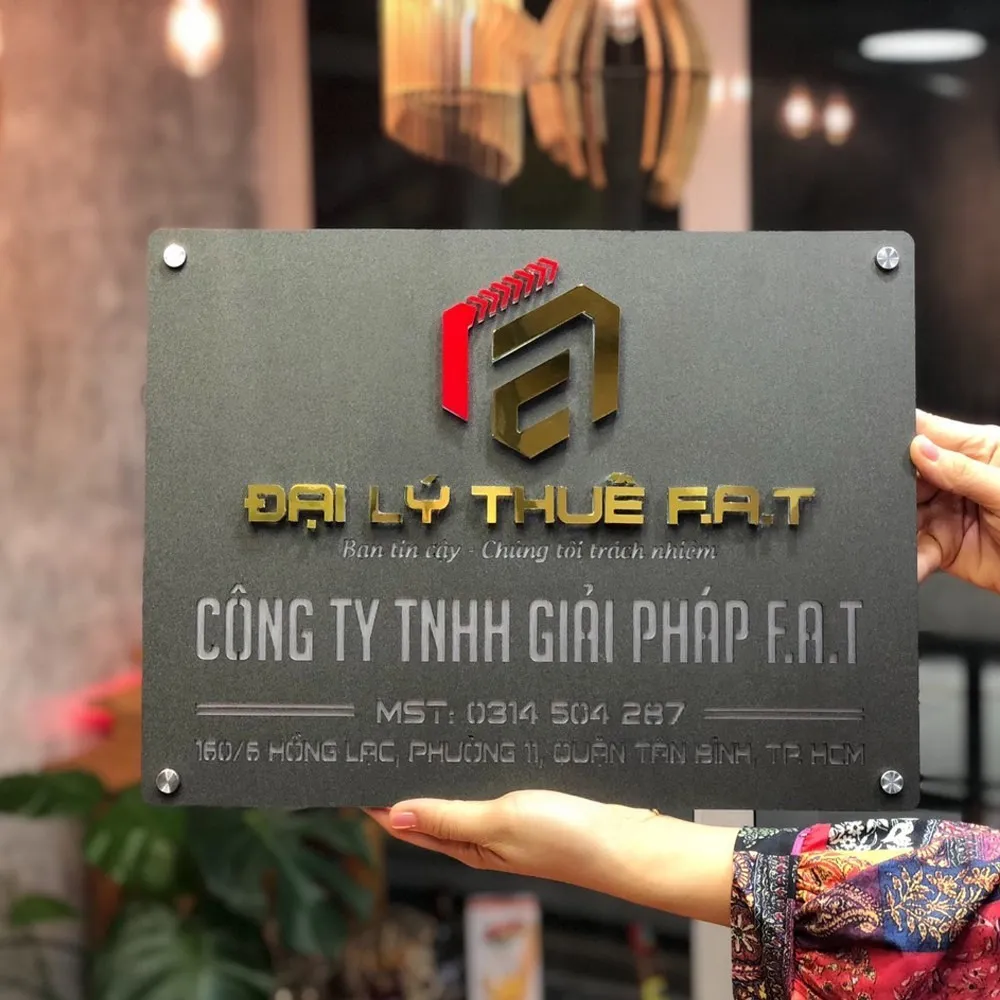 Bảng hiệu công ty inox xám khói logo nổi 3D đa màu – mặt trước tổng thể cầm tay Bảng hiệu công ty TNHH giải pháp F.A.T inox xám khói sơn tĩnh điện logo nổi 3D vàng đỏ bạc chữ nổi vàng
