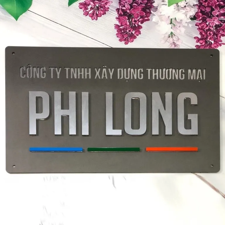 Mặt trước bảng hiệu công ty inox sơn tĩnh điện xám mờ, chữ nổi 3D inox trắng xước, thanh màu xanh dương – xanh lá – cam trang trí, cạnh vuông