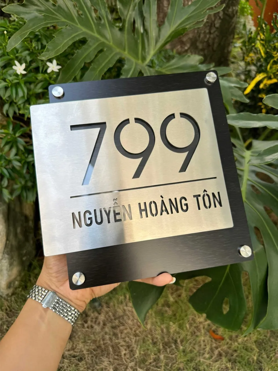 Bảng số nhà inox bạc xước — góc nghiêng trái thấy rõ lớp nền đen bên dưới Bảng số nhà inox cắt xuyên thấu nền đen số 799 cầm tay nhìn góc nghiêng trái