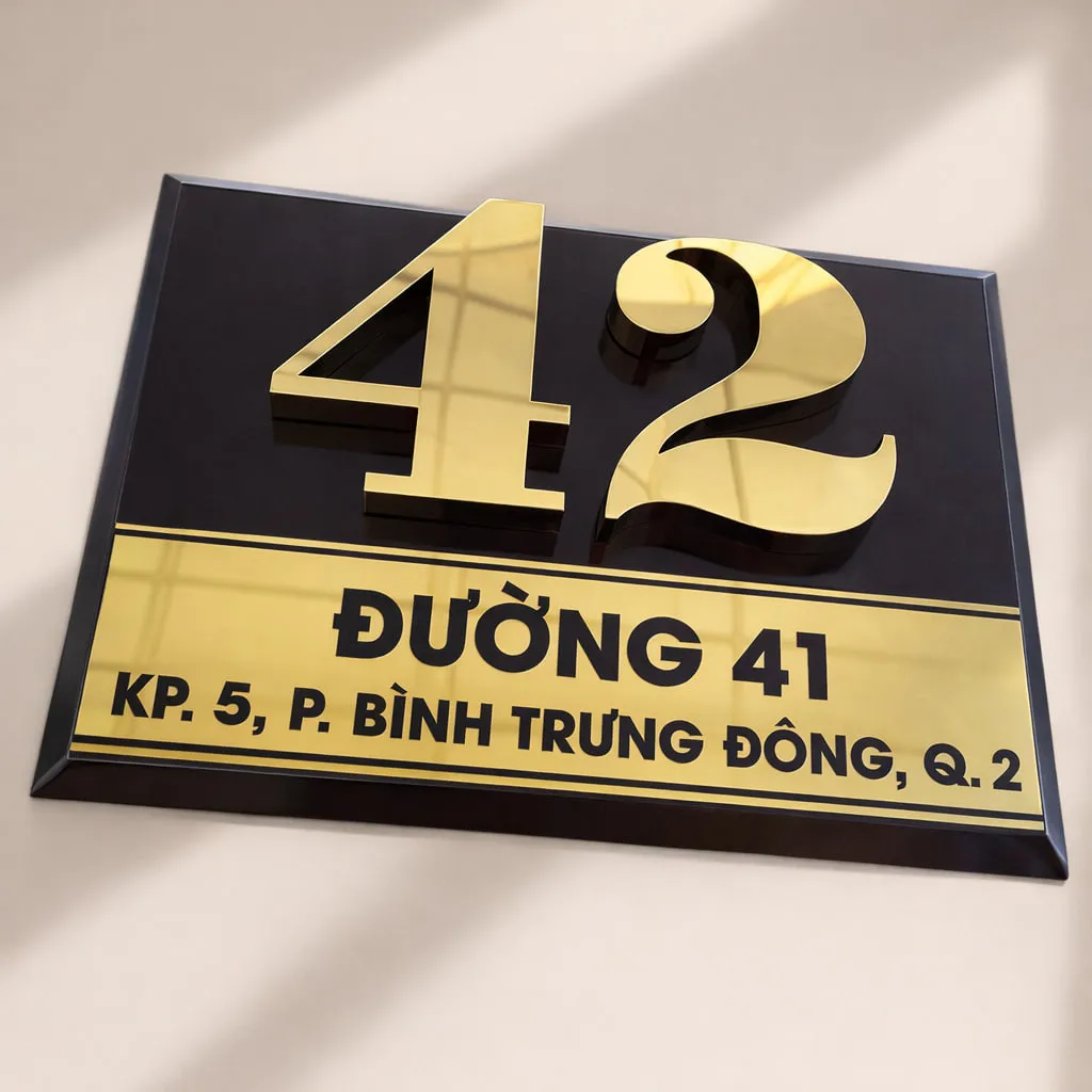 Bảng số nhà nền đen chữ vàng 3D – góc nghiêng cao thấy chữ nổi và viền vàng cạnh vát Bảng số nhà nền đen chữ vàng nổi 3D nhìn từ góc cao – thấy rõ chữ vàng gương nổi và cạnh vát vàng bóng