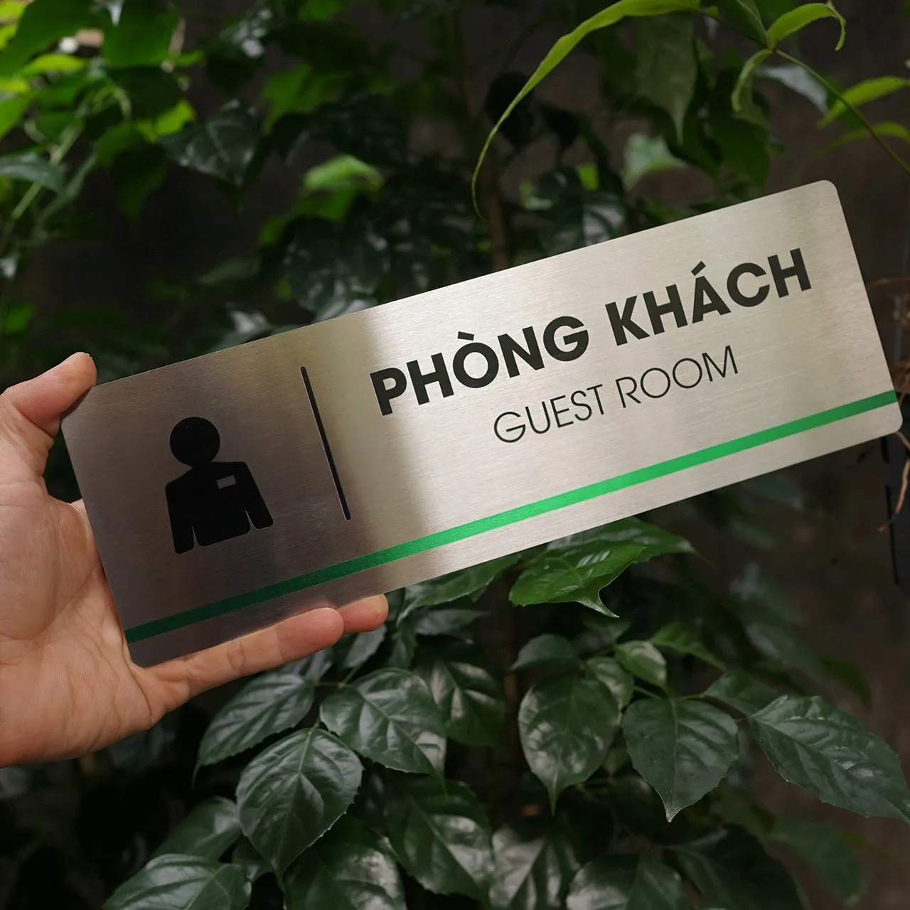 Bảng tên phòng khách inox 304 cầm tay nghiêng phải thấy rõ viền bo cạnh và sọc xanh lá