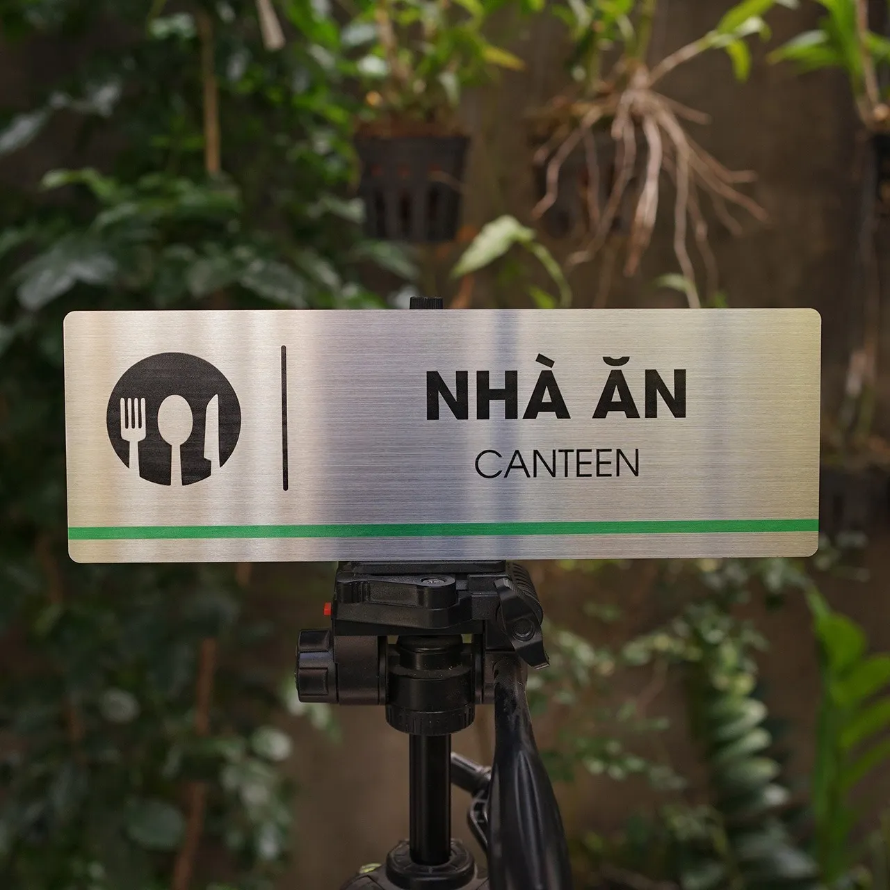 Bảng tên nhà ăn canteen inox 304 brushed cầm tay nhìn từ góc cao, thấy đủ icon và chữ NHÀ ĂN CANTEEN