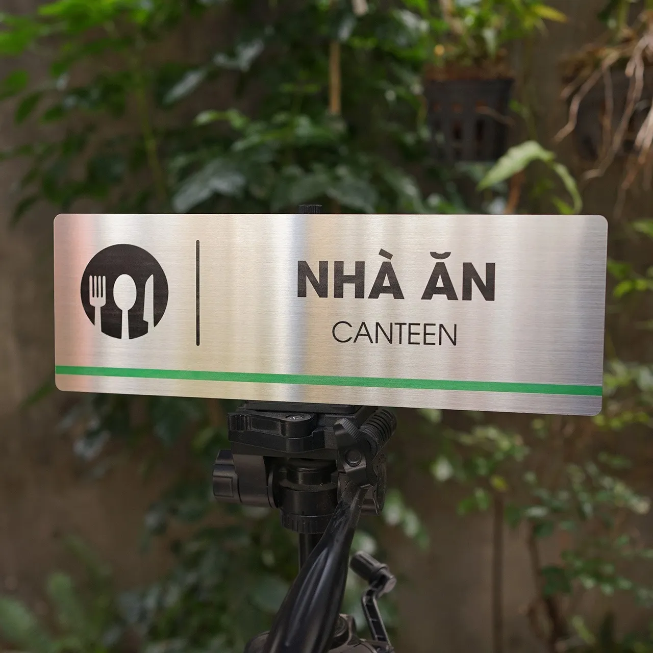 Góc nghiêng 45 độ bảng tên nhà ăn canteen inox 304 brushed, thấy rõ icon đĩa nĩa và sọc xanh lá