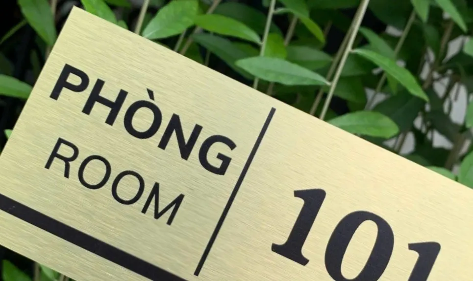 Cận cảnh chữ và đường kẻ thiết kế trên bảng số phòng inox vàng xước Cận cảnh bố cục chữ PHÒNG ROOM và đường kẻ dọc trên bảng số phòng inox