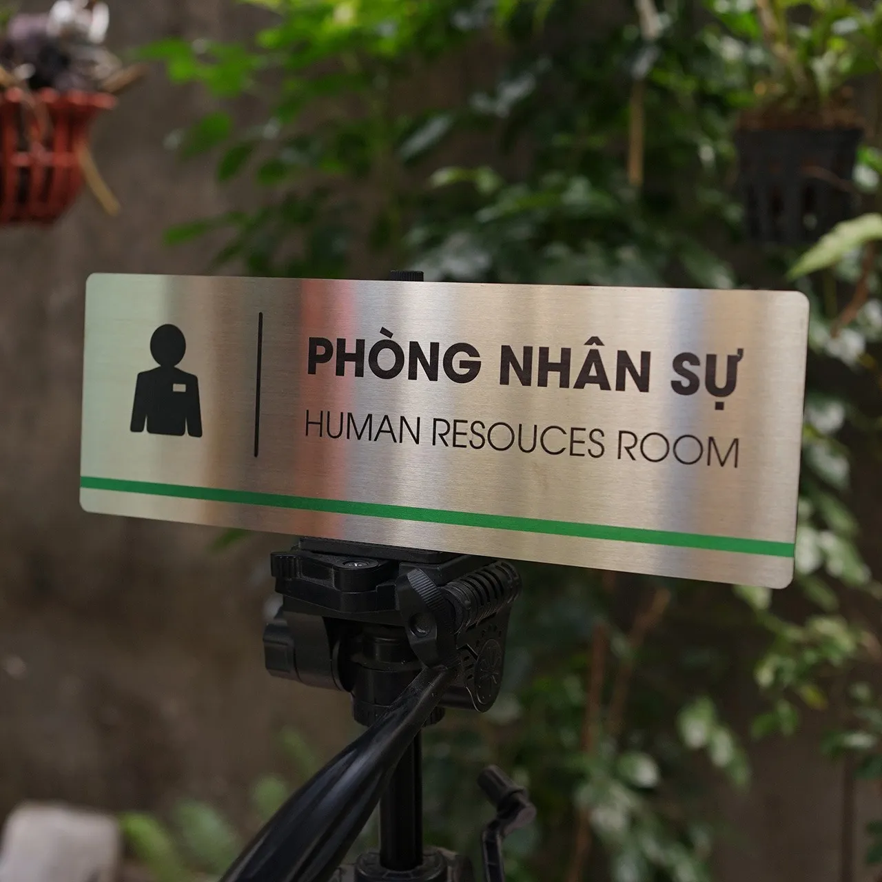 Bảng Tên Phòng Nhân Sự Inox 304 – Góc Thấp Thấy Rõ Sọc Xanh Lá Trang Trí Bảng tên phòng nhân sự inox 304 trên giá đỡ nhìn góc thấp thấy rõ sọc xanh lá phía dưới